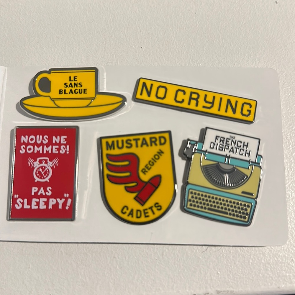 5 enamel pins from the movie the French Dispatch. No crying typewriter mustard